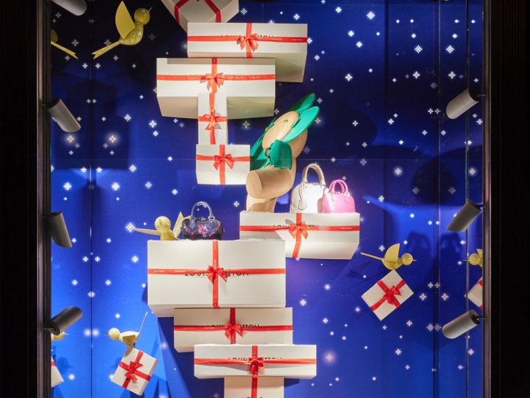 Festive window display of stacked white gift boxes against a starlit backdrop
