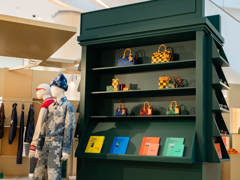 Green retail shelving unit styled with handbags, mannequins and colour-blocked boxes