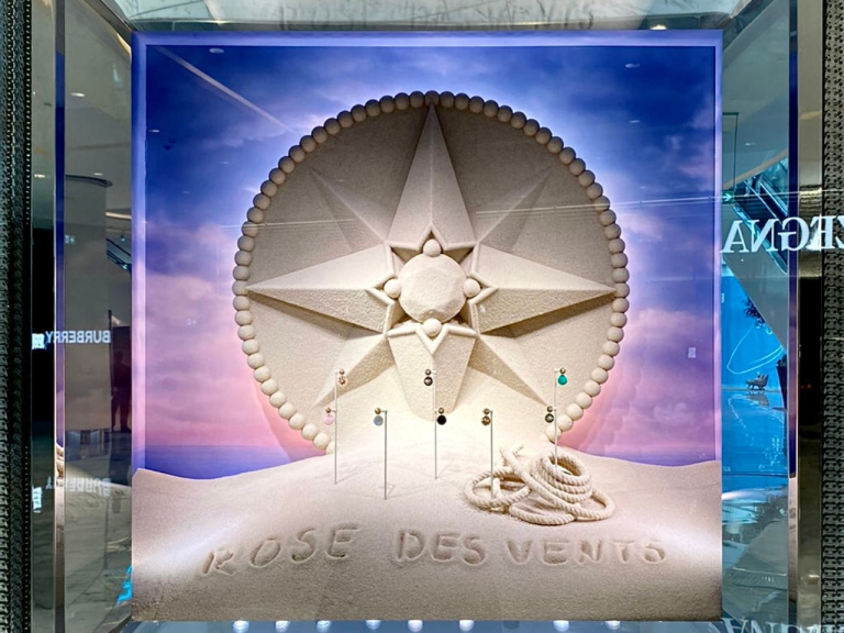 Jewellery window display with a sculpted star emblem set in a sand-dune scene