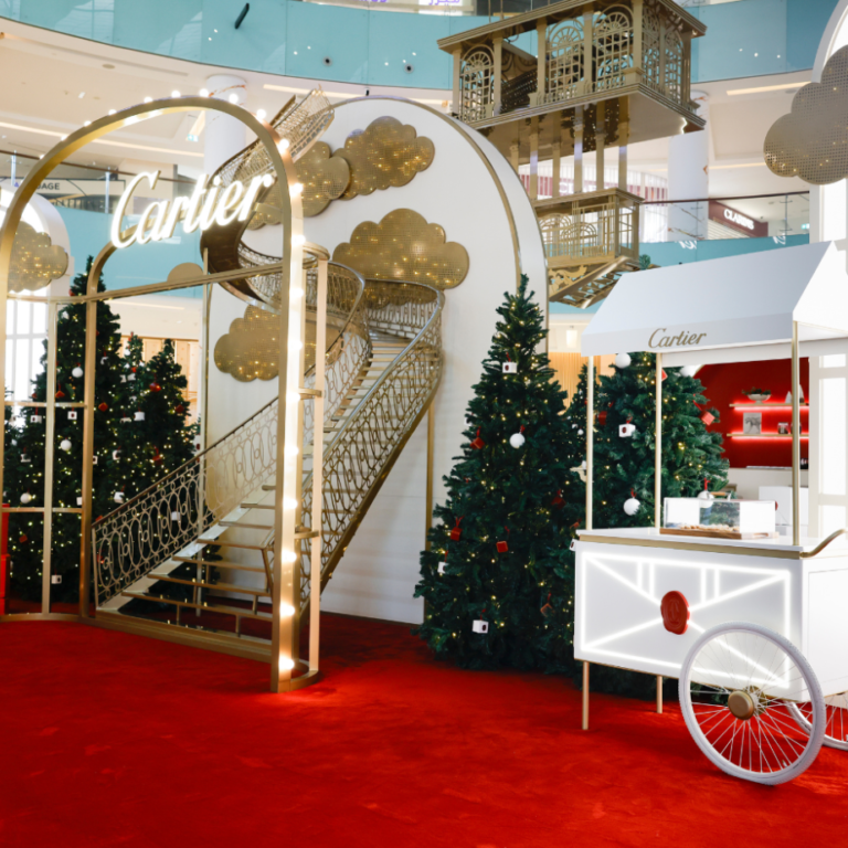 Cartier festive installation with a gold arch, red carpet and decorated cart